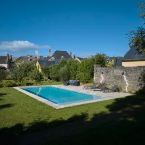 Élégante piscine 11x5m avec liner gris clair, margelles en travertin et volet immergé. Confort et technologie réunis pour un espace raffiné – Bonheur Piscines.