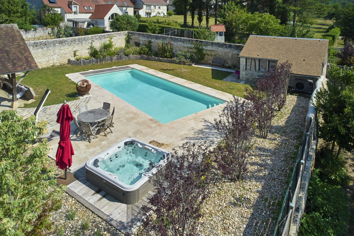 Une piscine classique de 13 x 5 m à l’élégance naturelle, habillée d’un liner sable et entourée de travertin beige. – Hénocque Piscines et Spas