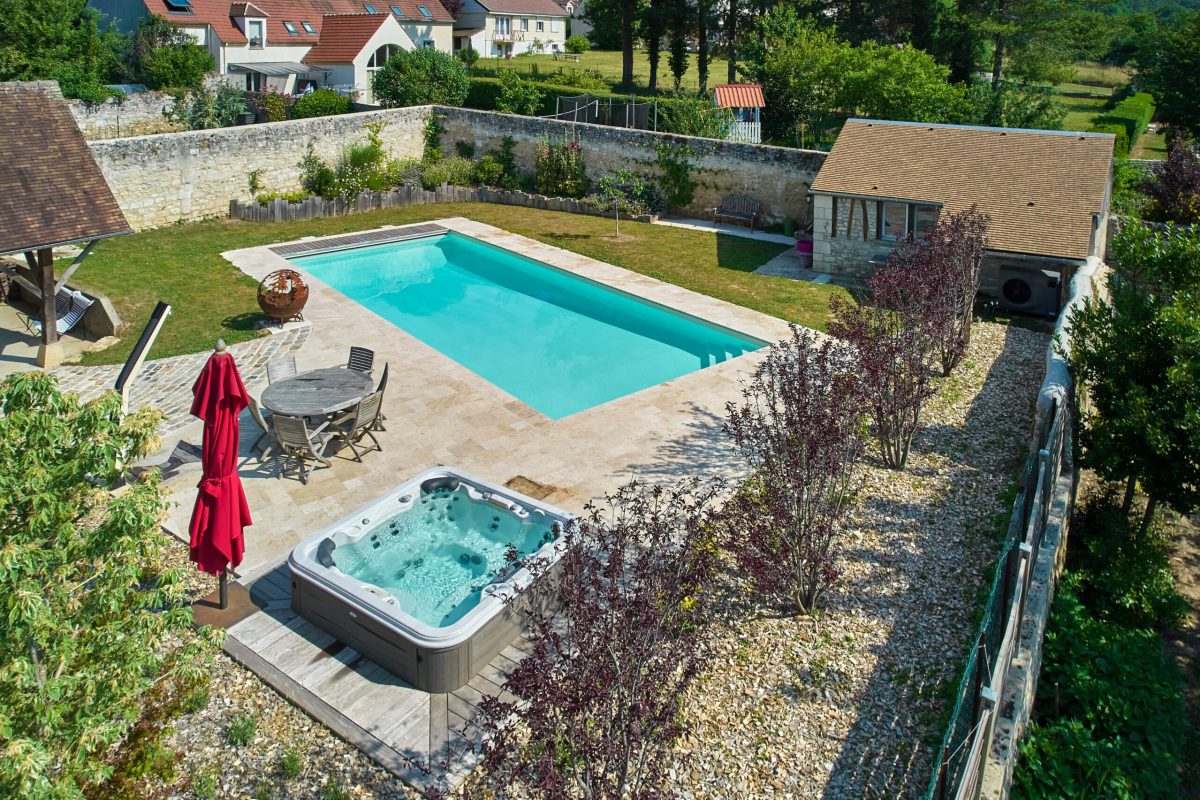 Une piscine classique de 13 x 5 m à l’élégance naturelle, habillée d’un liner sable et entourée de travertin beige. – Hénocque Piscines et Spas