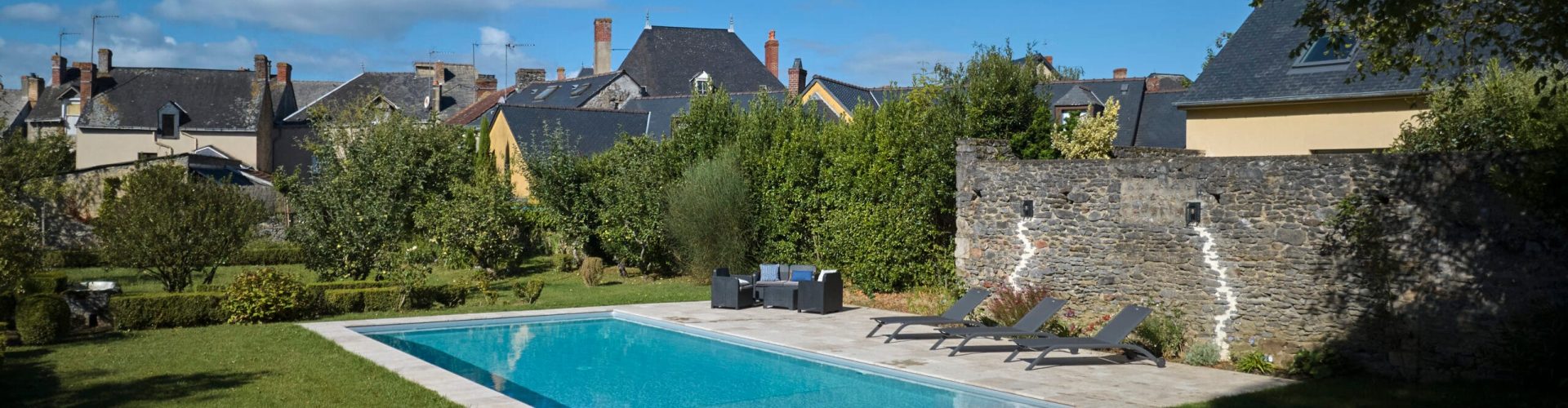 Élégante piscine 11x5m avec liner gris clair, margelles en travertin et volet immergé. Confort et technologie réunis pour un espace raffiné – Bonheur Piscines.